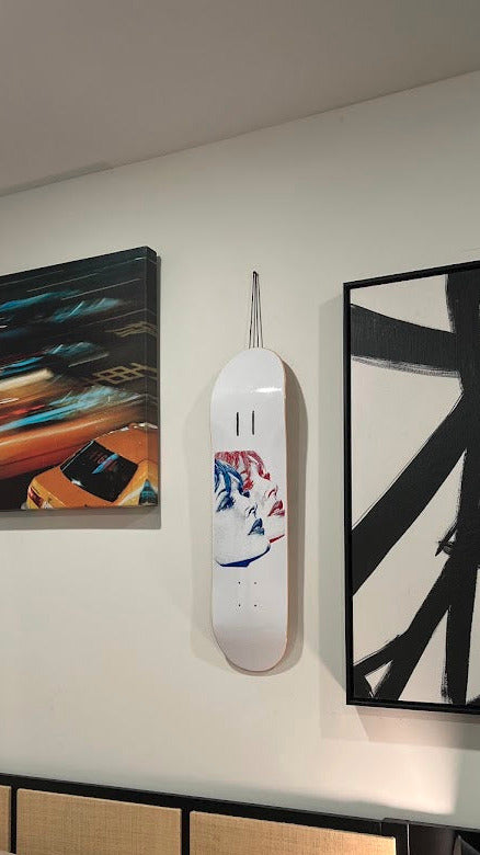 Decorative skateboard wall art above a bed with abstract paintings on the wall.